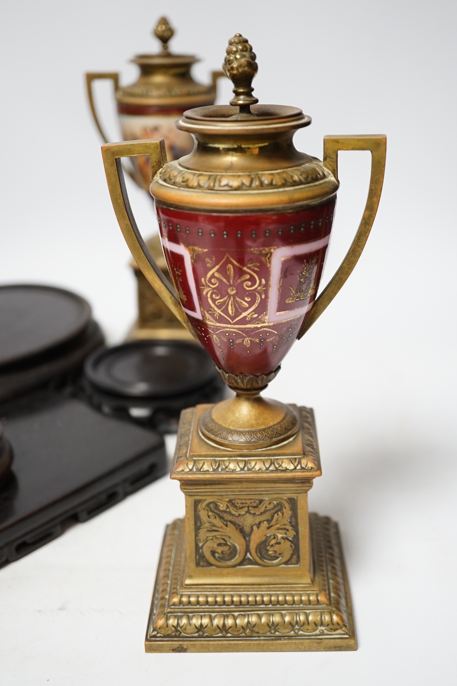 A pair of Vienna style brass mounted urns with enamelled classical scenes and six various Chinese carved hardwood stands, 23cm high